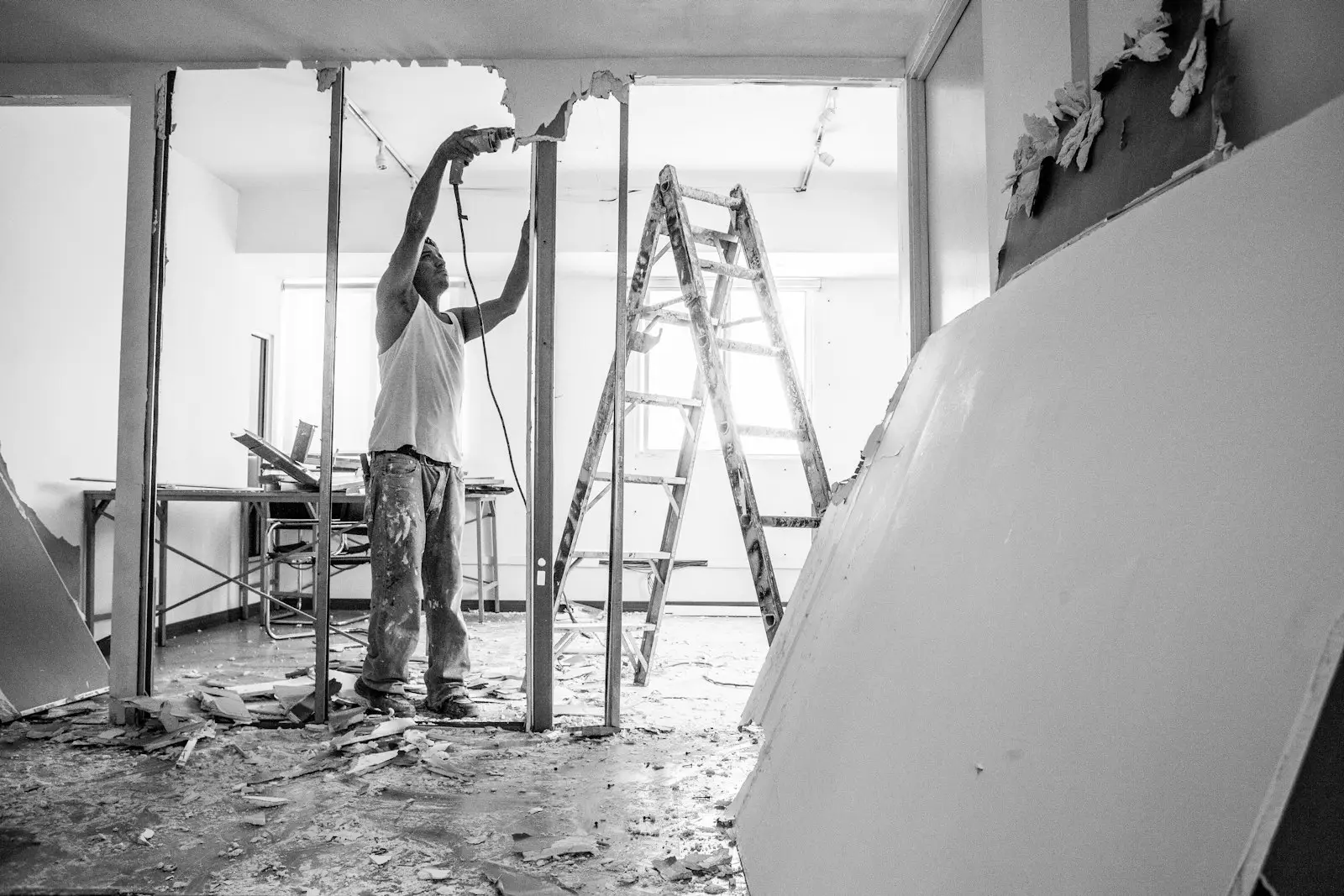 A builder working on a ladder in a room being renovated