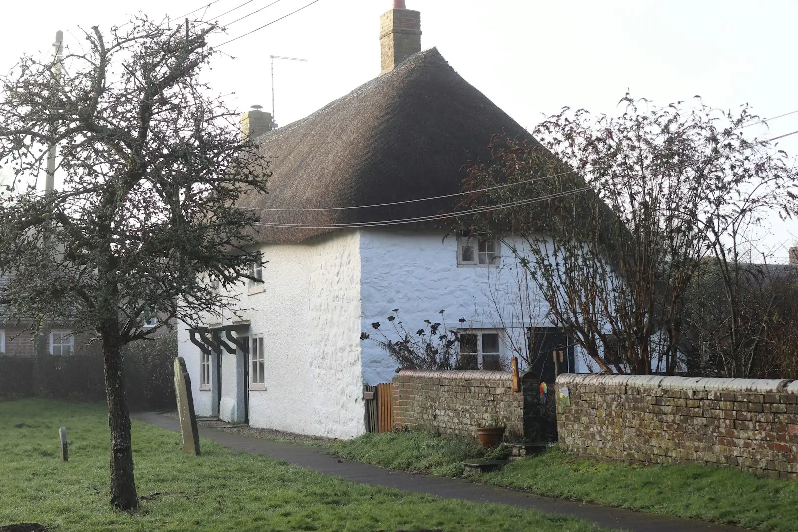 A white Devon cottage with a thatched roof and stone wall